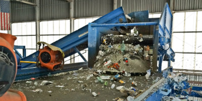 Mixed orecycling goes down a conveyer belt with fans blowing off the lightest items.