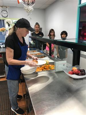 cafeteria worker serves students in line