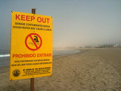Yellow sign on beach says not to swim because of sewage