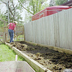 long garden with a person layering compost on top