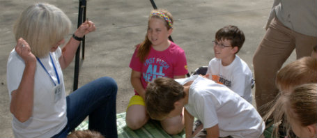 A teacher shows students a compost bin